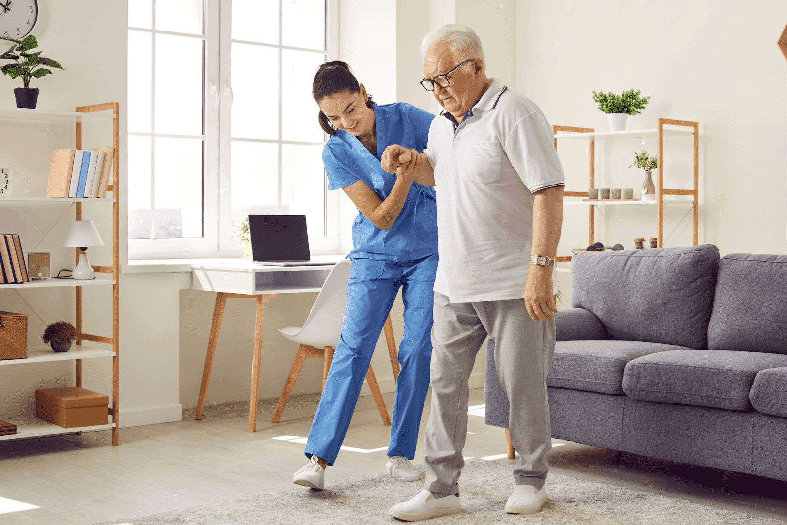 A caregiver supports an elderly man as he walks.