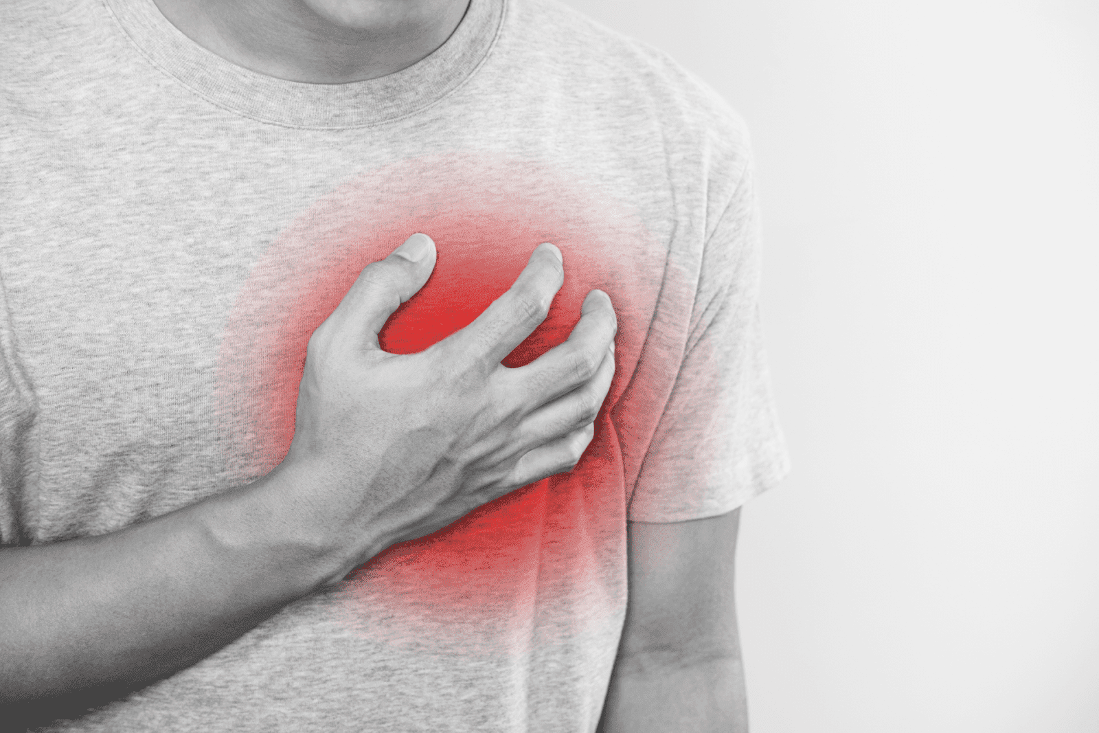 A close-up of a person’s hand pressed against their chest, with a red overlay emphasizing pain or pressure.