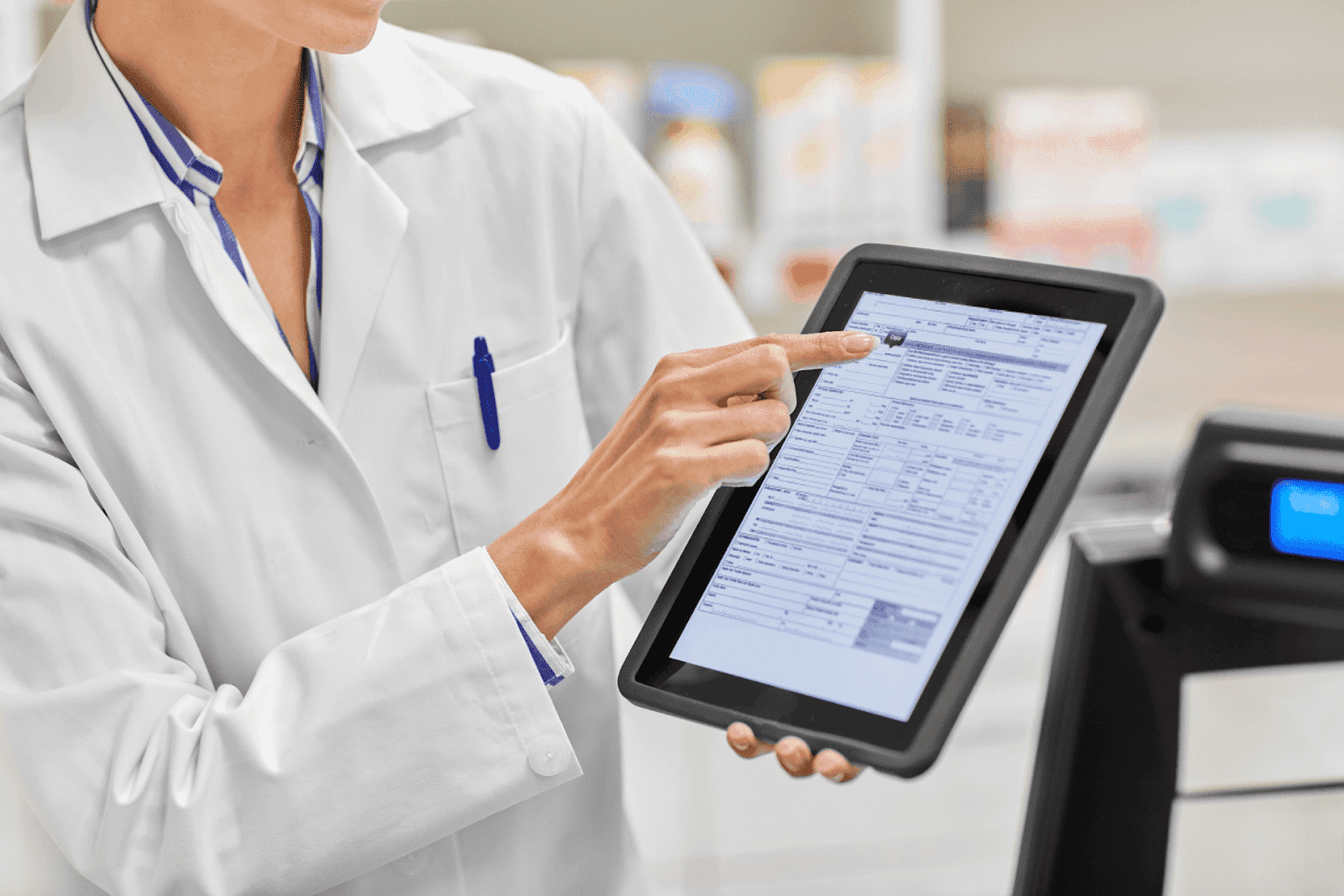 A doctor in a white coat uses a tablet to review a medical prescription