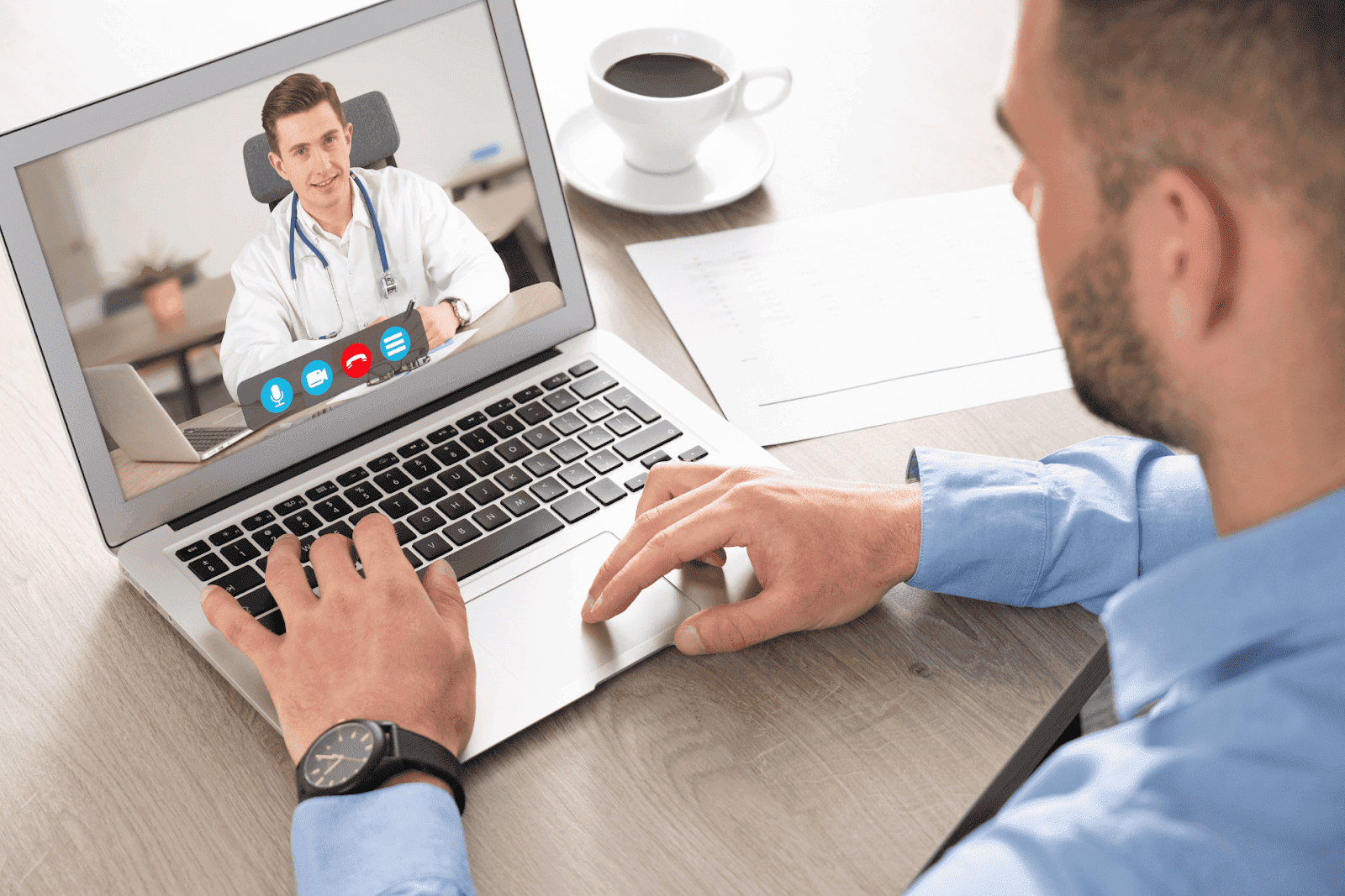 A man having a video call with a male doctor on a laptop screen during an online medical consultation. A Man having an online video consultation with a smiling doctor on his laptop.
