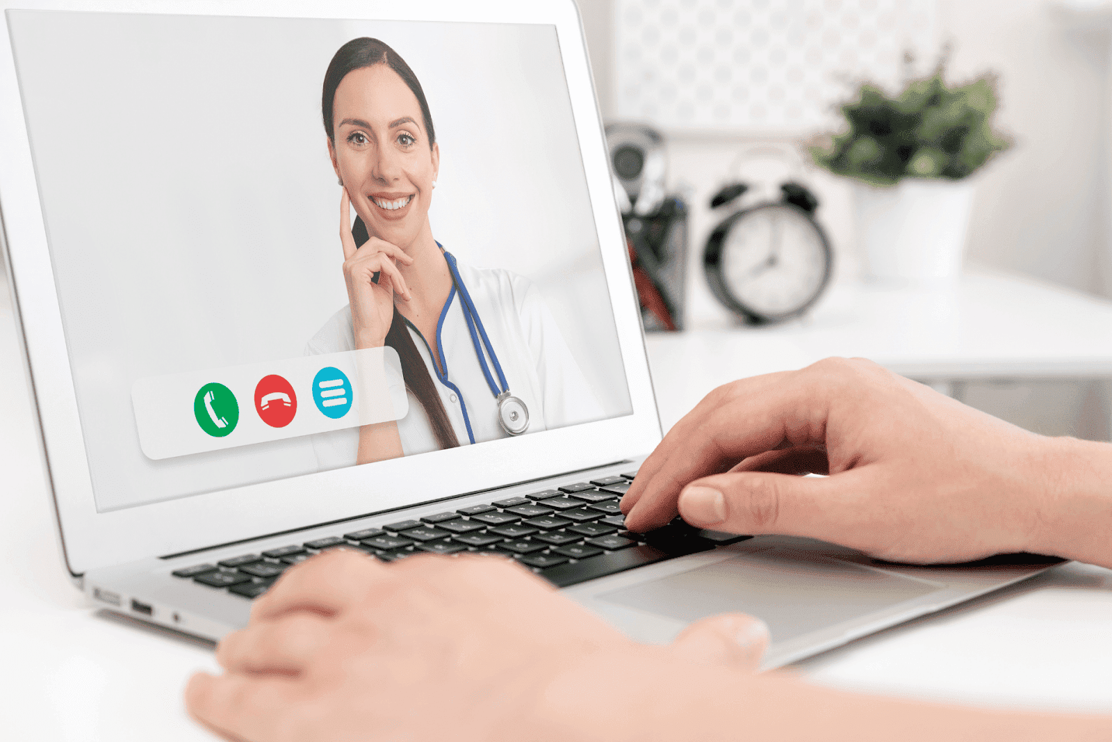 A person engaging in a telehealth consultation with a smiling doctor visible on the laptop screen.