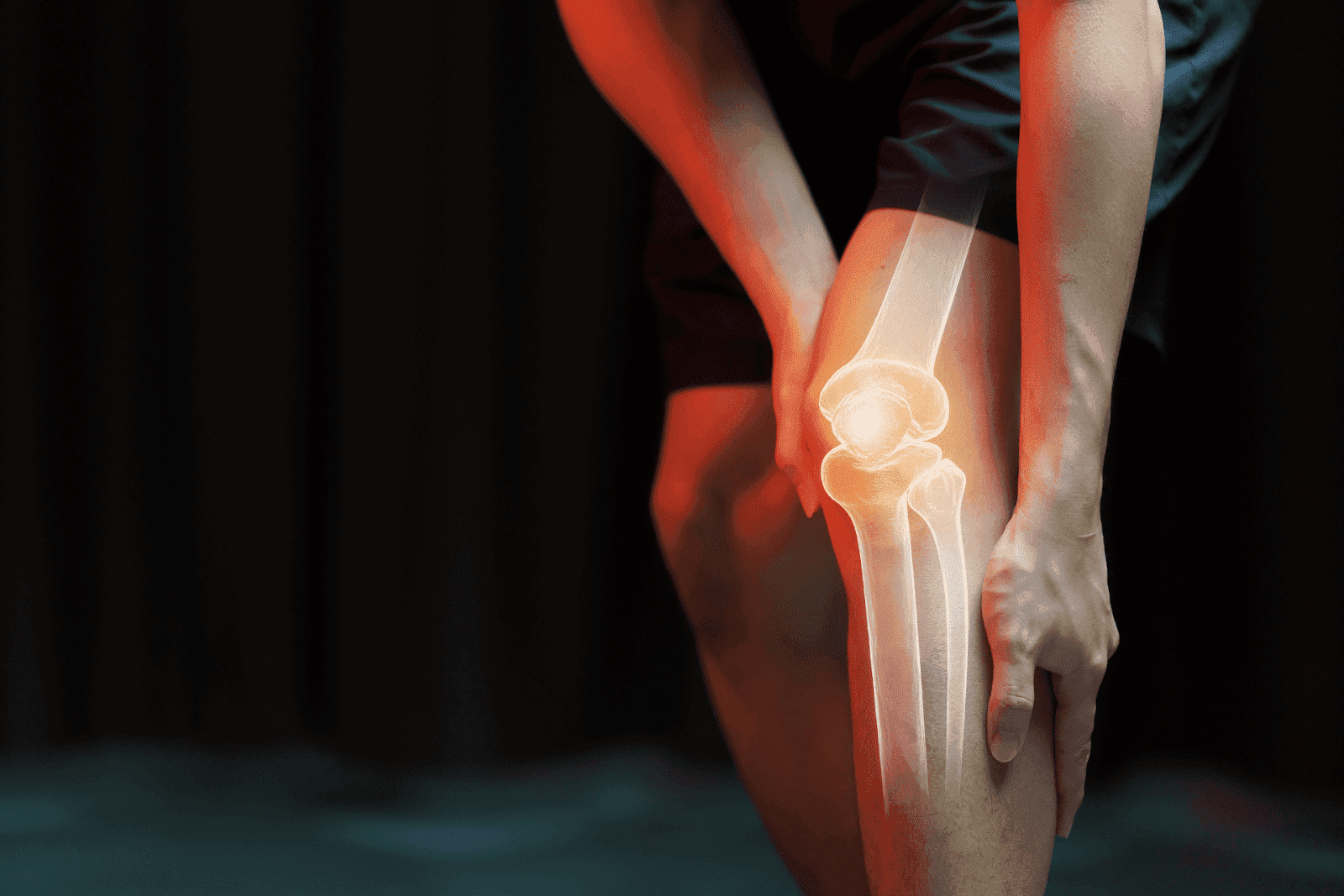 A person holds their knee with the joint highlighted in red