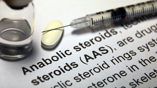 Syringe containing an anabolic steroid resting on a pill