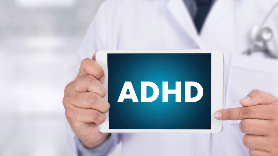 Doctor holding tablet that says "ADHD" and pointing to it.