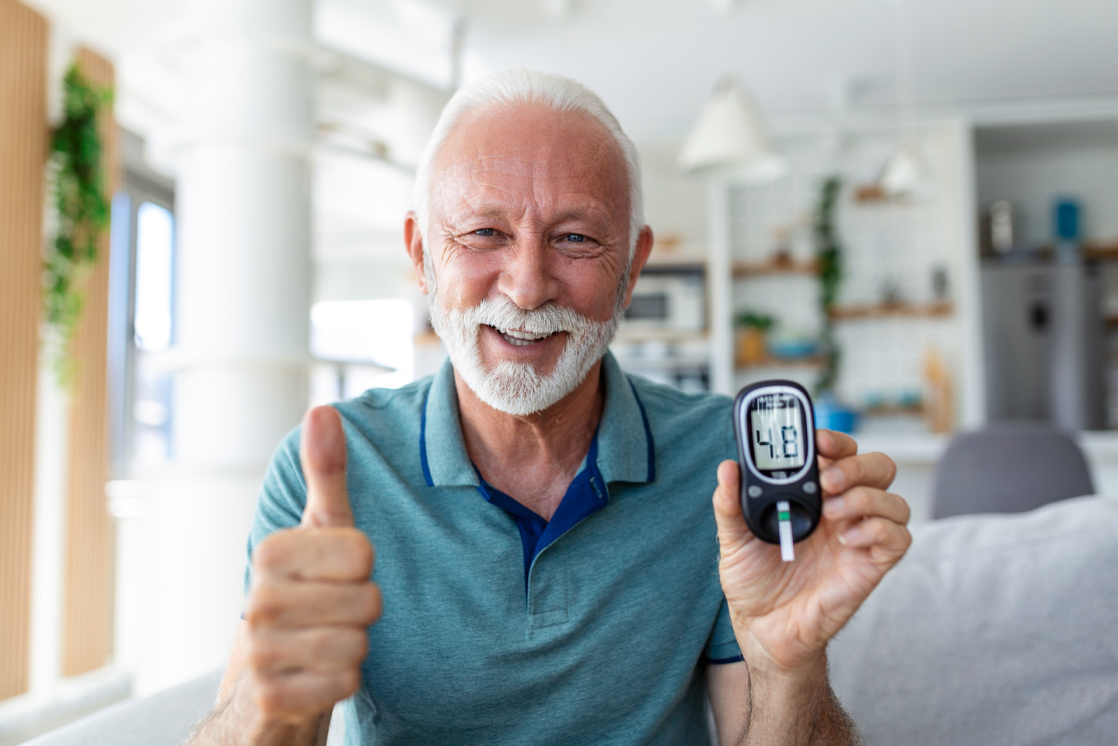 An older man smiling and giving a thumbs-up while holding a glucose meter that displays 4.8.