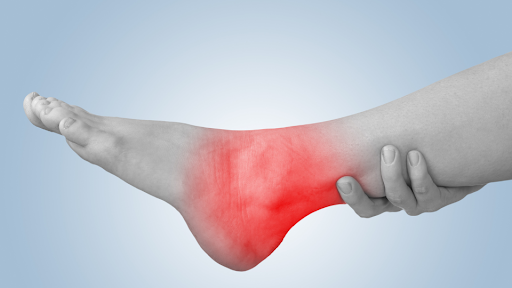 Person holding up leg and ankle highlighted in red implying pain.