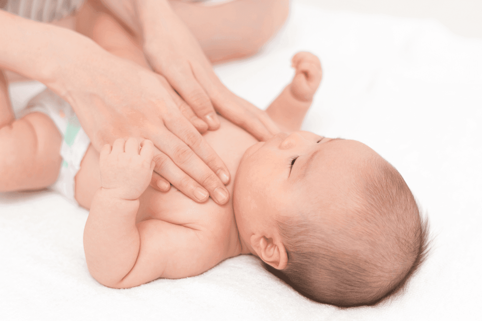 Baby lying while being gently massaged on the chest.