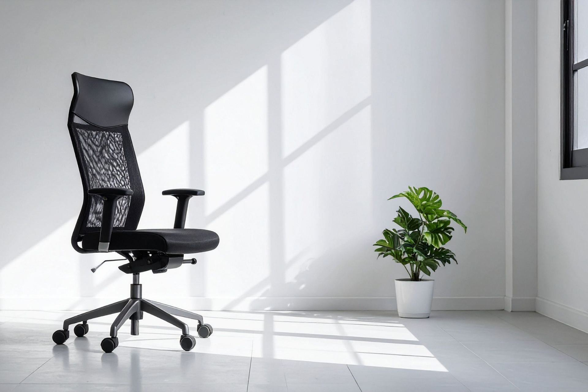 Black ergonomic office chair beside a potted plant in a bright room