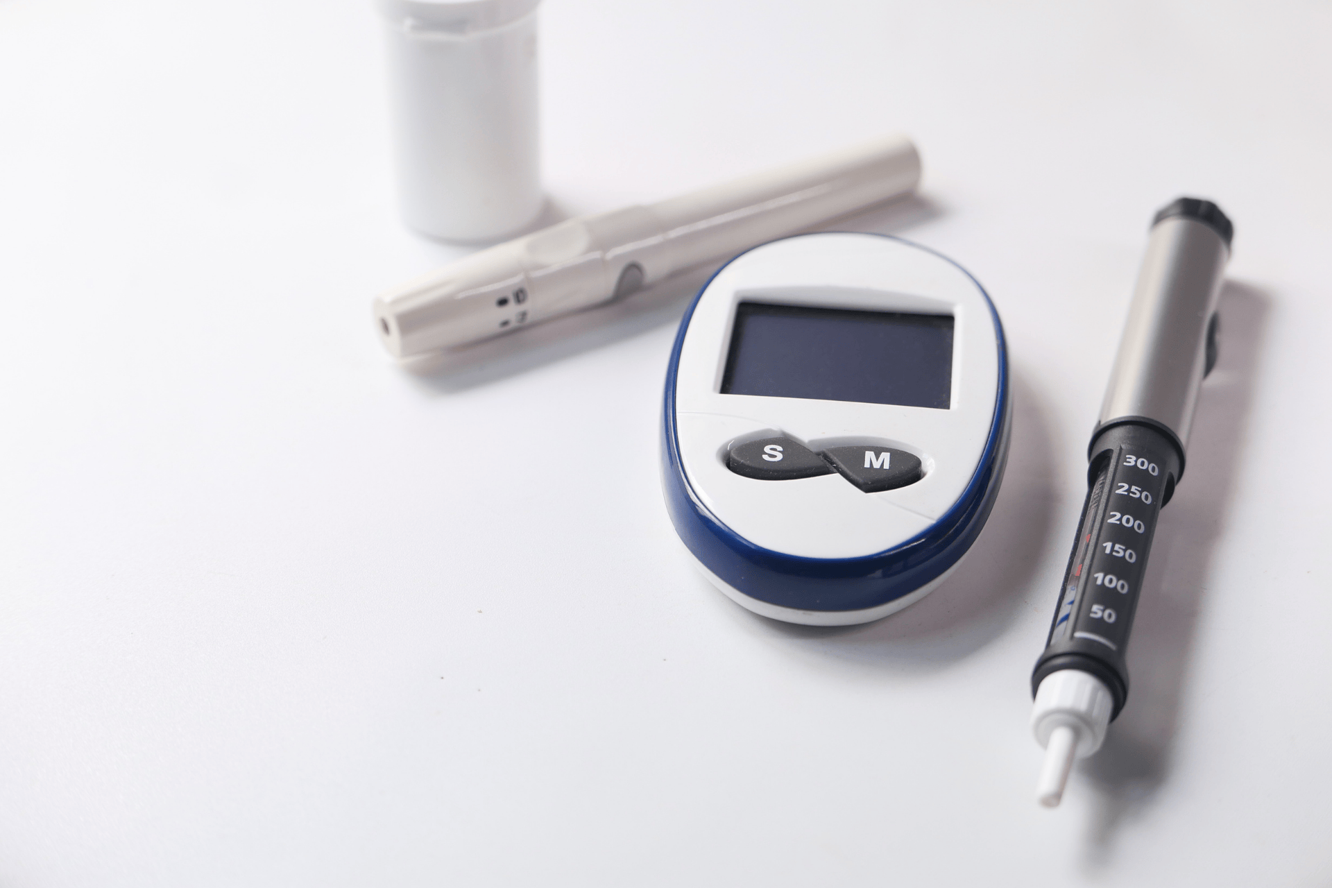 Blood glucose meter and insulin pen on a white surface.
