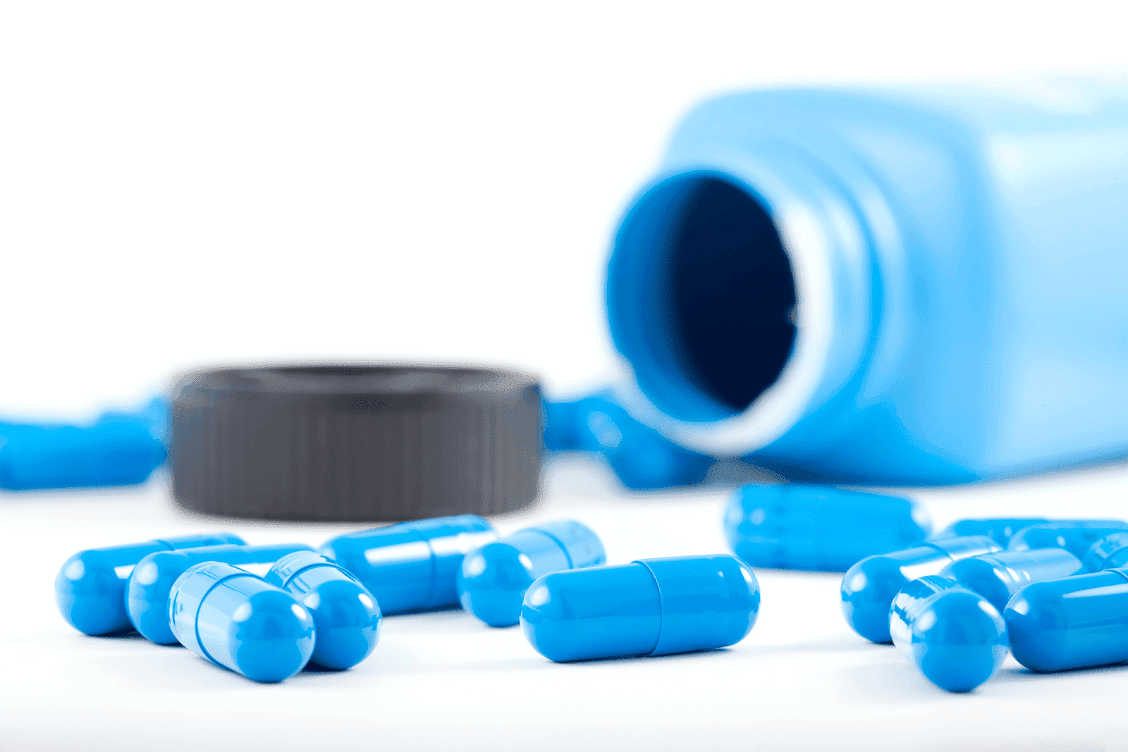 Blue capsules spilled from an open pill bottle.