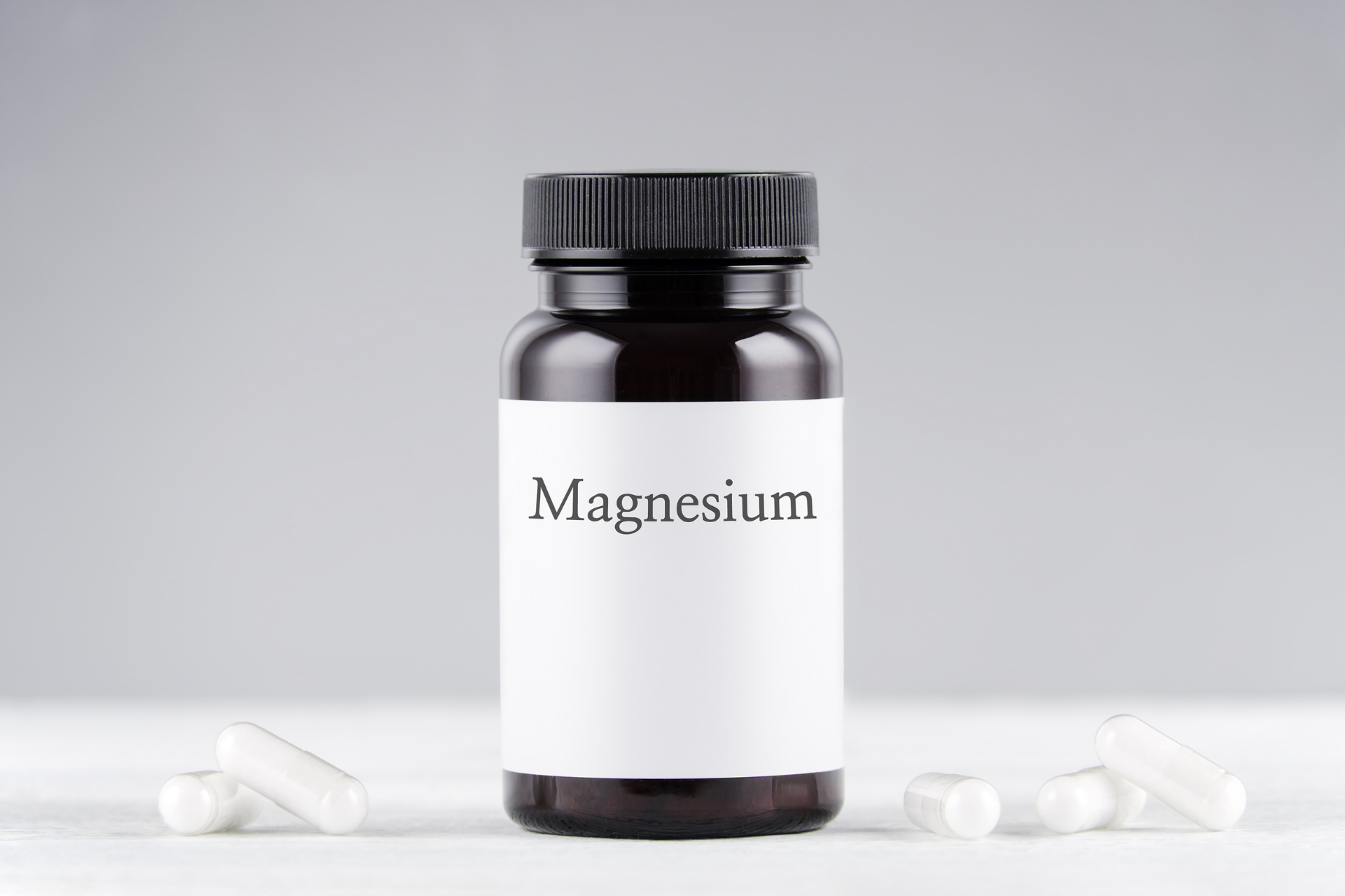 Bottle labeled “Magnesium” with capsules placed beside it