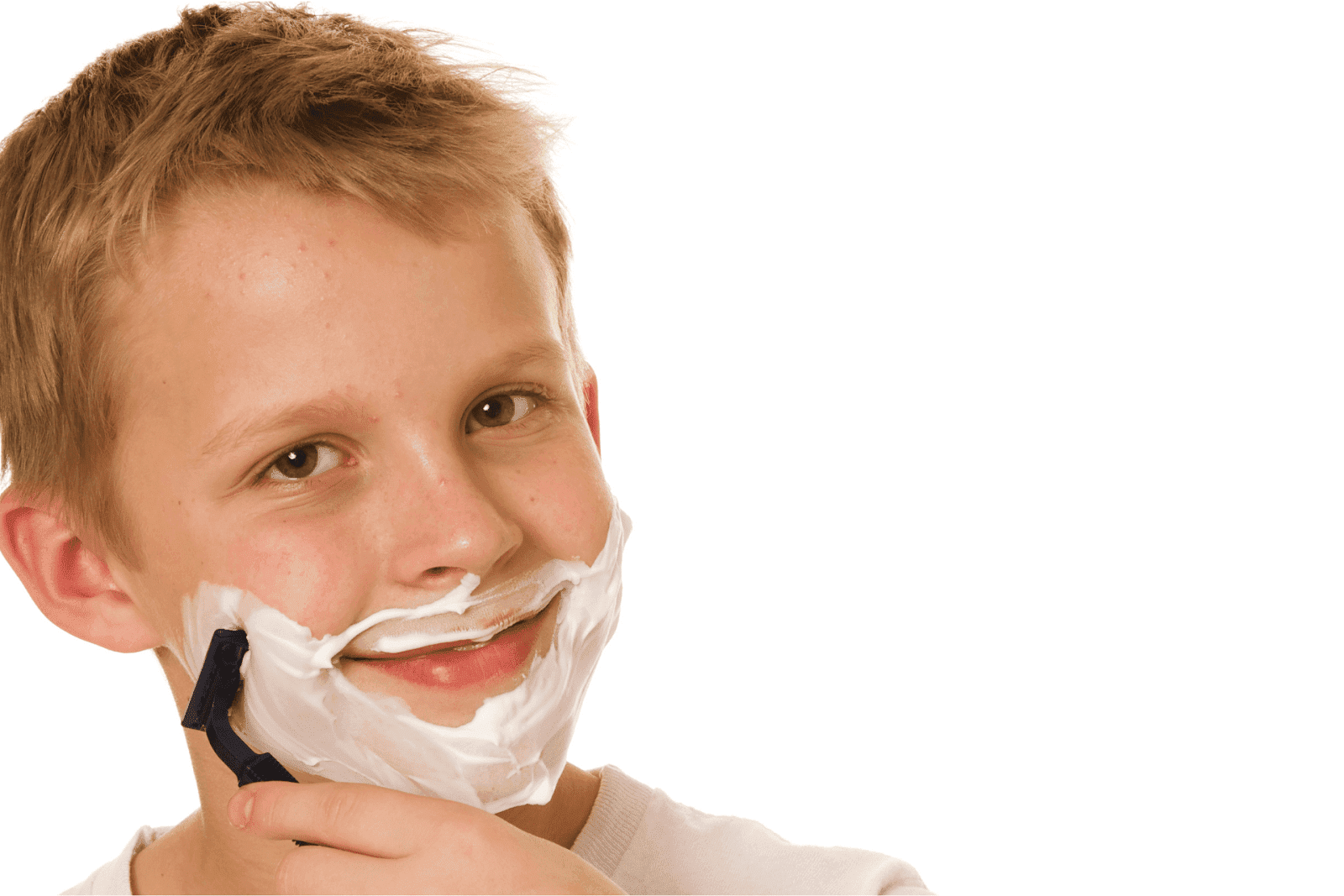 Boy smiling while shaving with foam on his face.