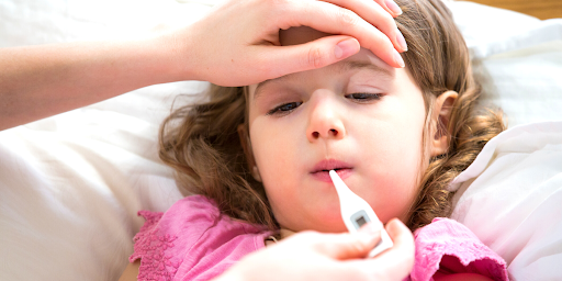 young girl getting her fever checked with a digital thermometer