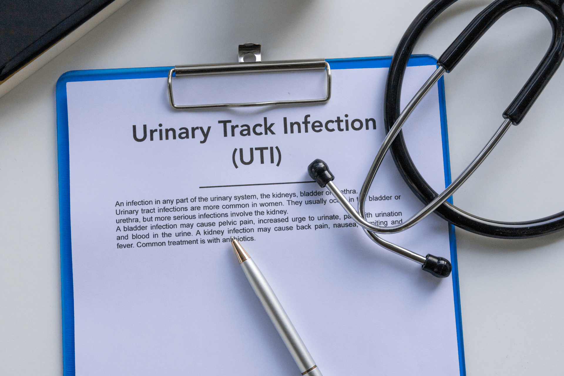 Clipboard with a document titled ‘Urinary Tract Infection (UTI)’ beside a stethoscope.