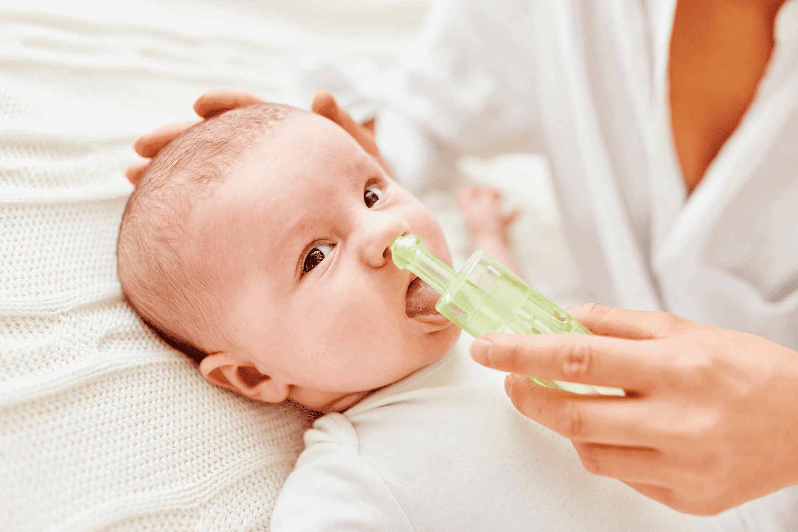 Close-up of a baby having their nose cleaned with a nasal aspirator.