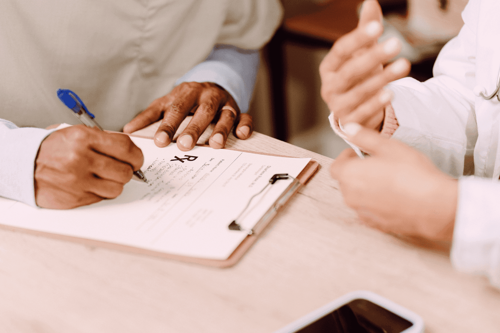 Close-up of a person filling out a prescription form on a clipboard