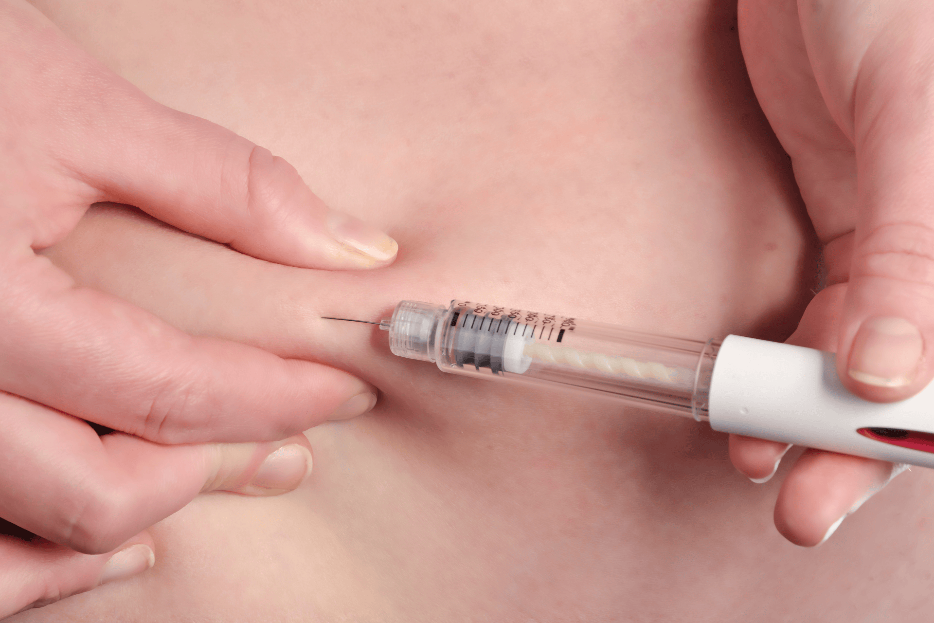 Close-up of a person injecting medication into their abdomen with a syringe pen.
