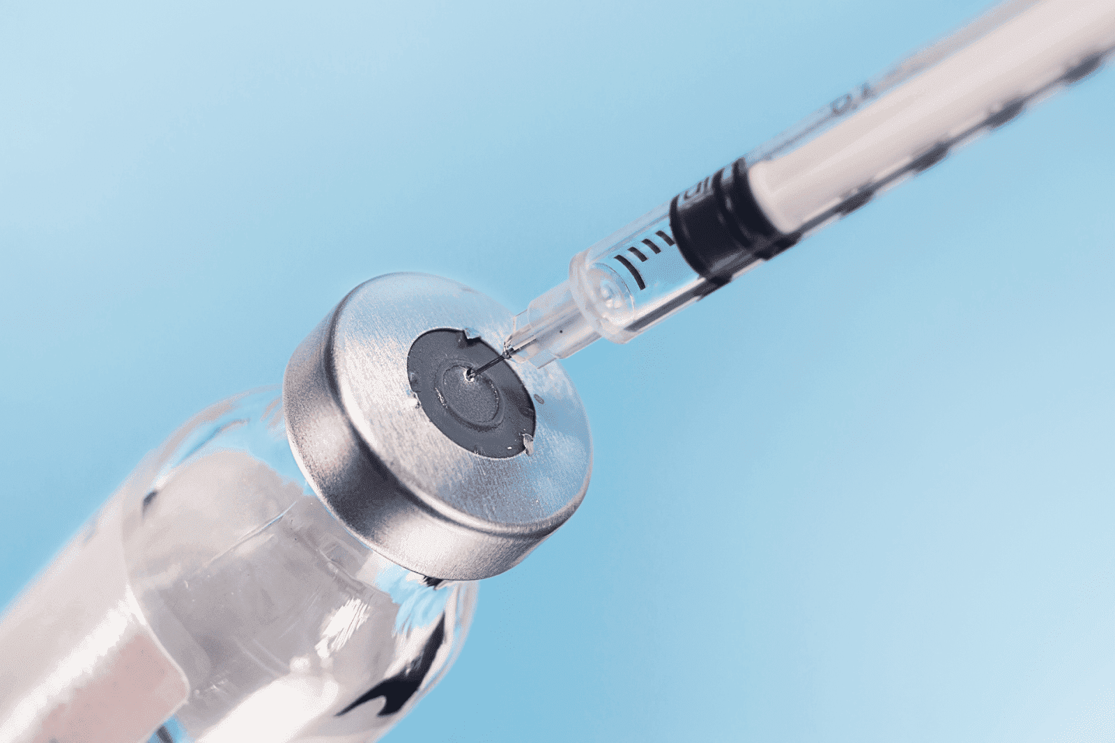 Close-up of a syringe drawing liquid from a medical vial.
