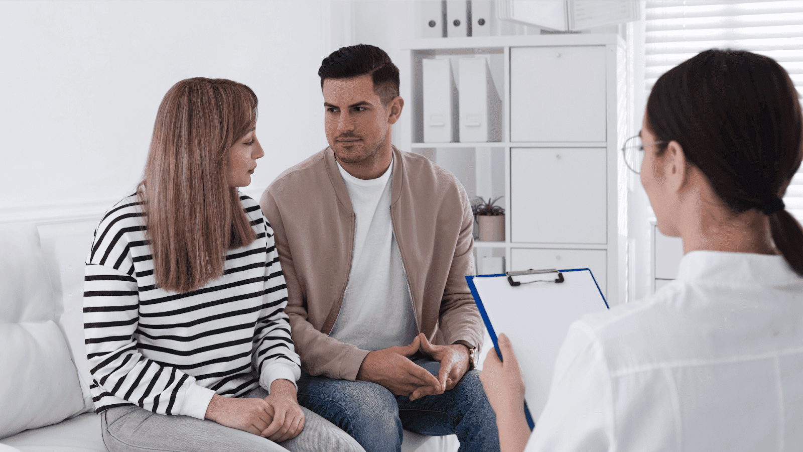 Couple speaking with a healthcare professional in a medical office.