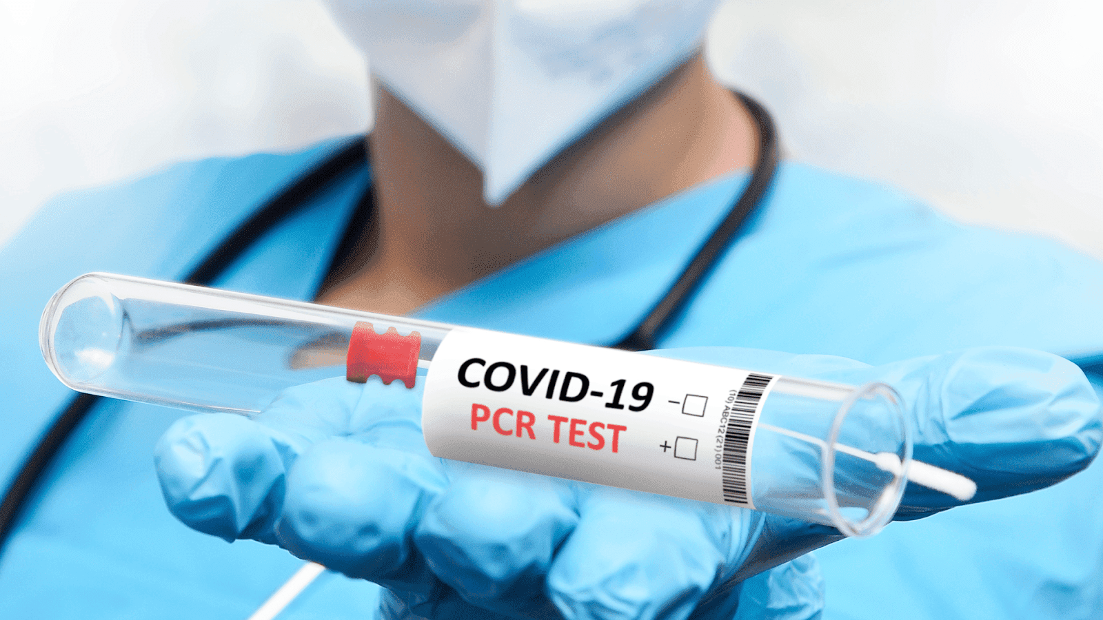 A close-up of a healthcare worker’s gloved hand holding a COVID-19 PCR test tube