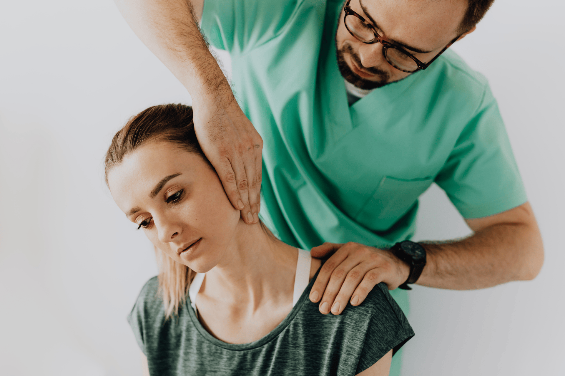 A woman with a cervical strain sits with her head tilted to the side while a healthcare provider supports her neck and shoulder during evaluation.