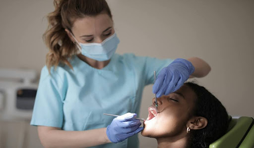A Dentist carefully inspects a patient's teeth with a dental mirror.