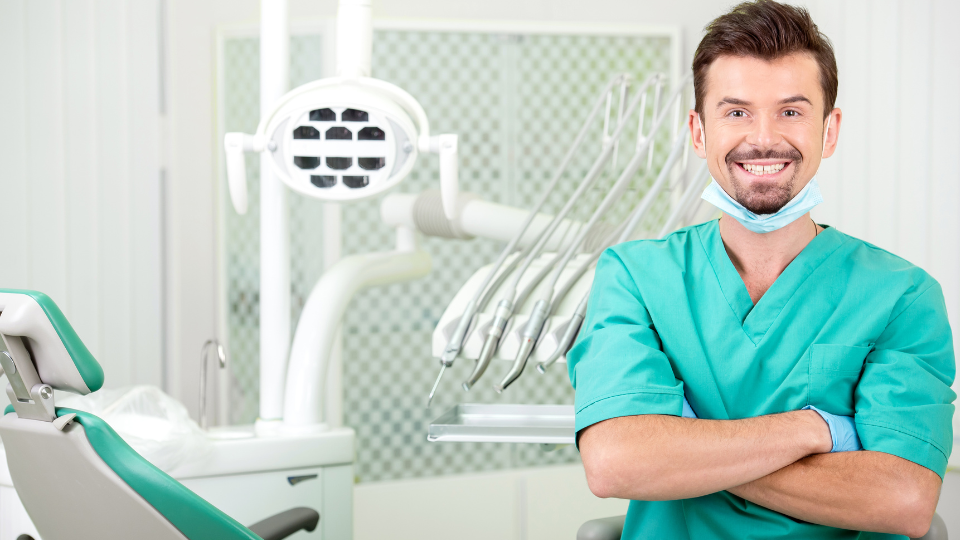 Dentist smiling with dental chair in background