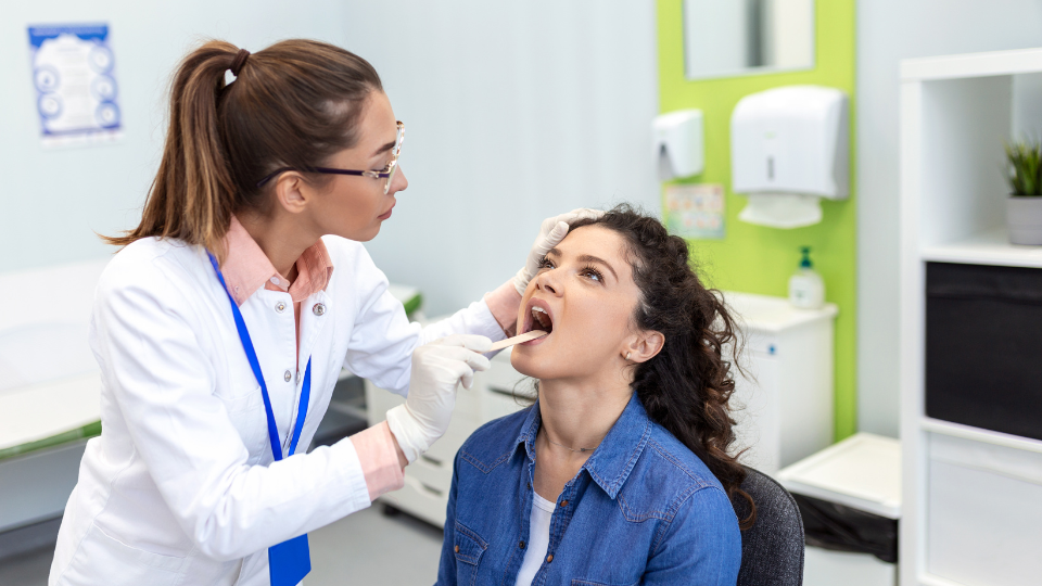 Doctor checking female patient for strep