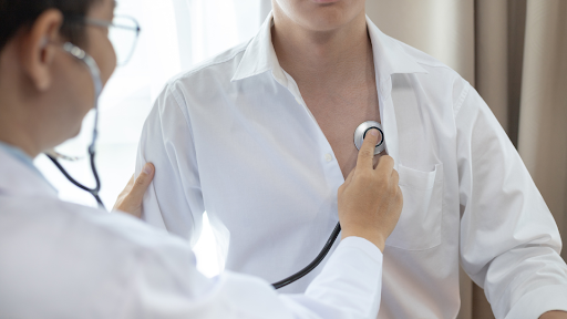 Doctor using stethoscope to check patient's heartbeat.
