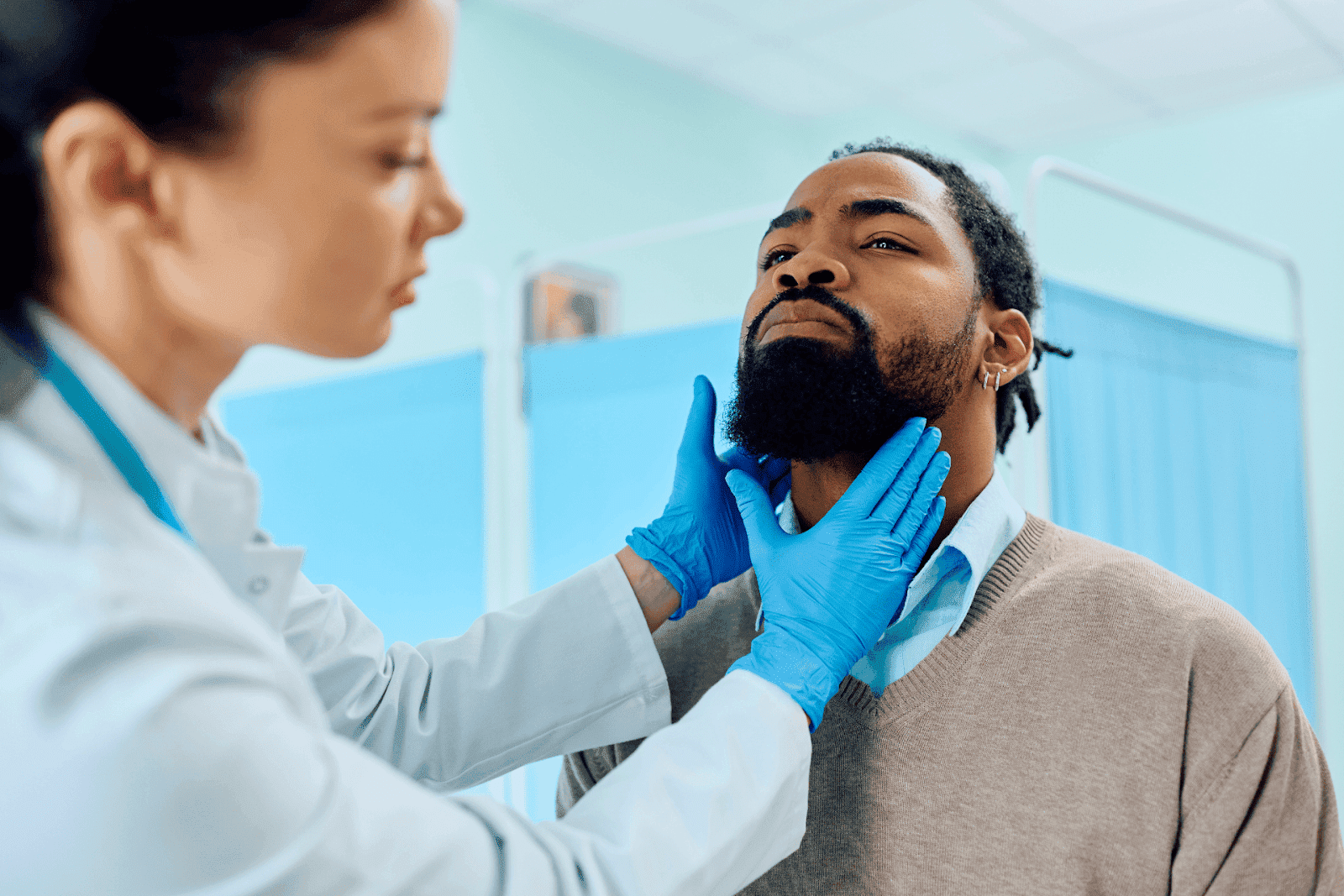 Doctor examining a man’s throat with gloved hands