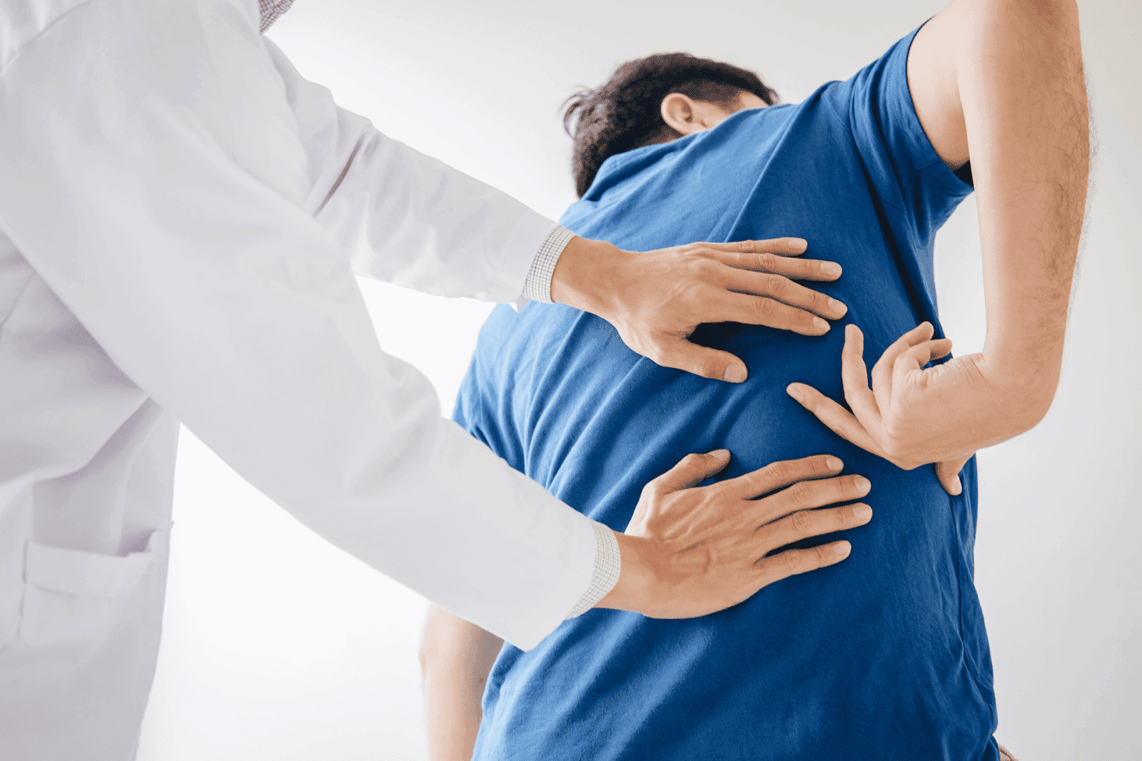 Doctor examining a patient's lower back for discomfort.