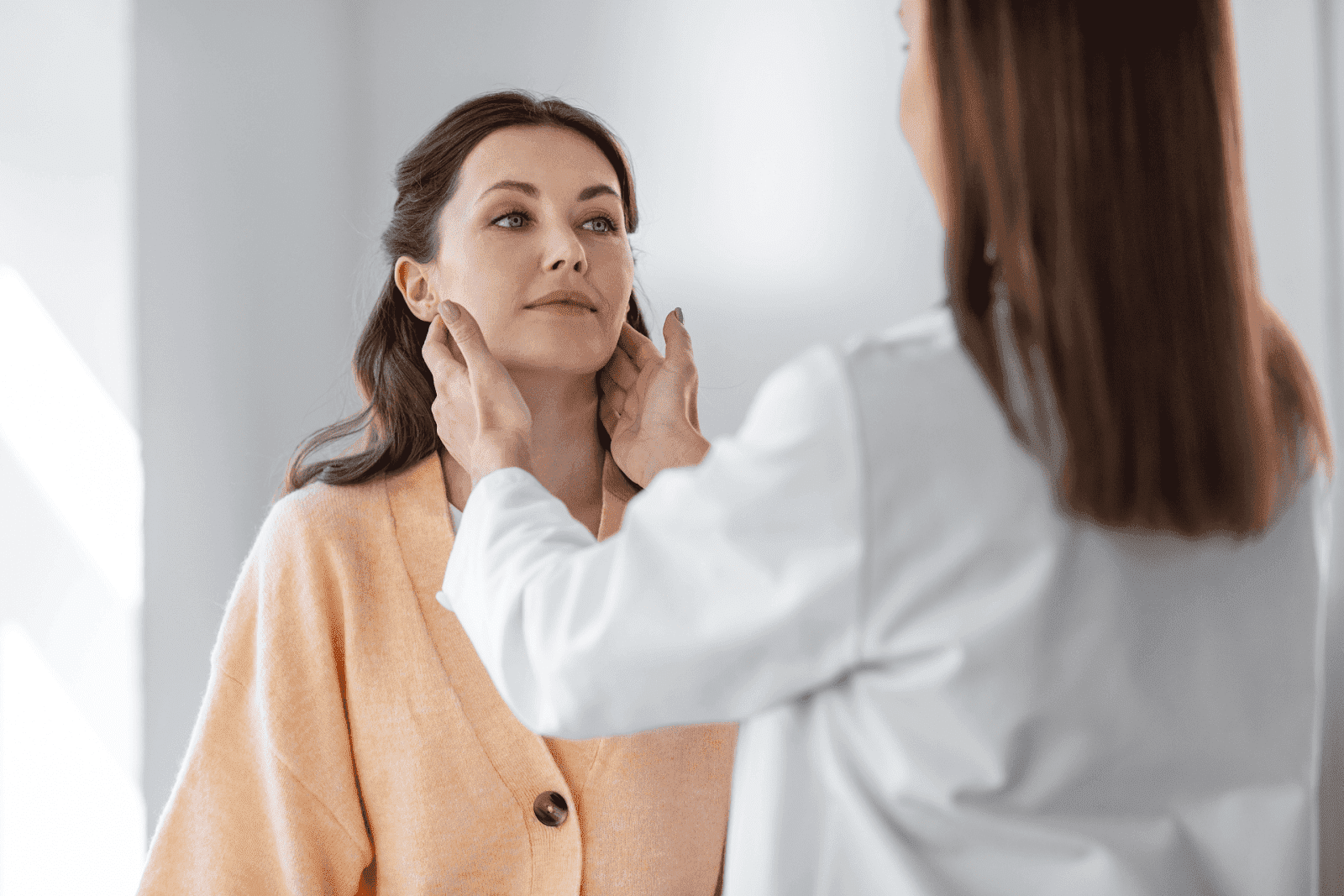 Doctor examining a woman’s neck by palpating lymph nodes