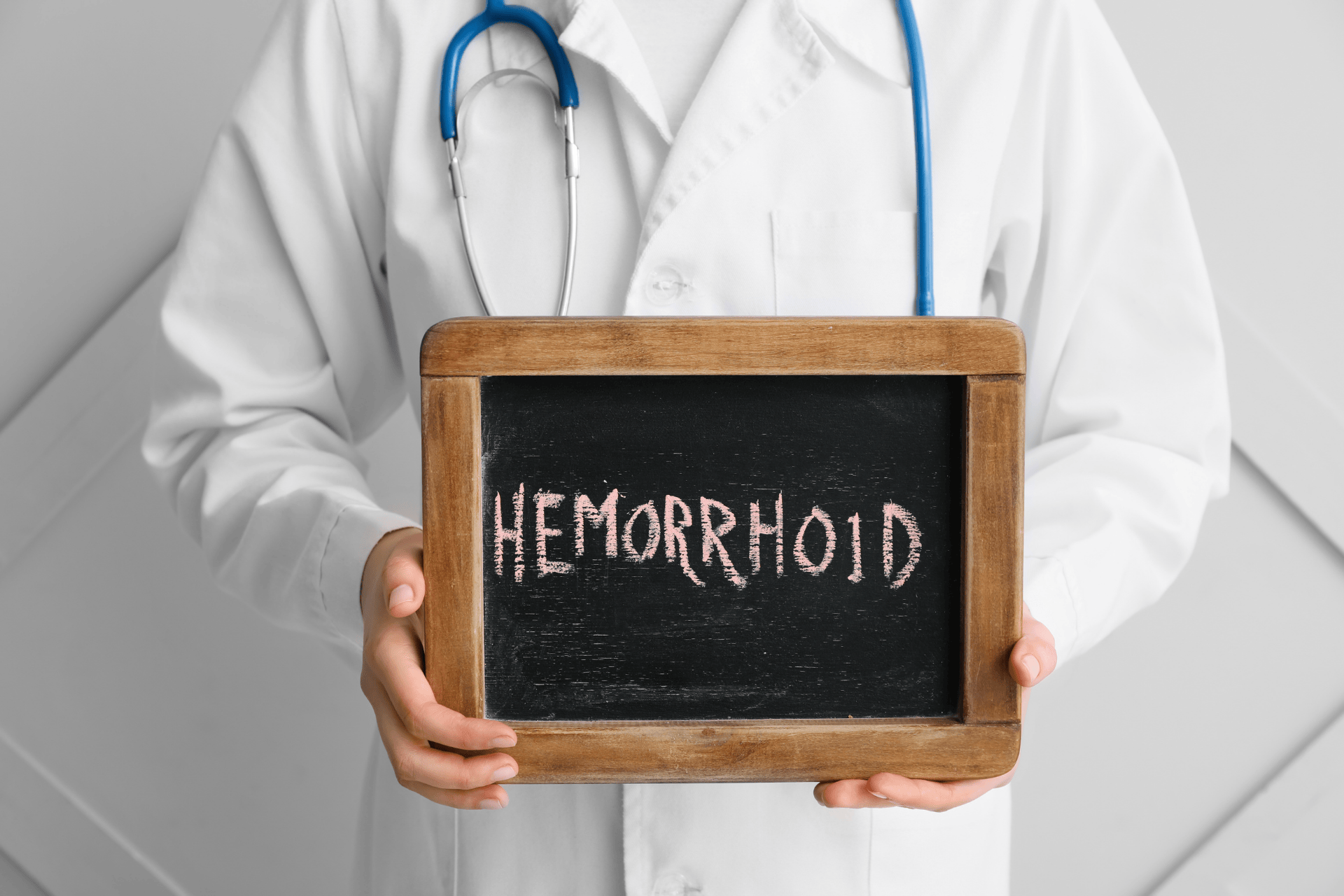 Doctor holding chalkboard spelling hemorrhoid.