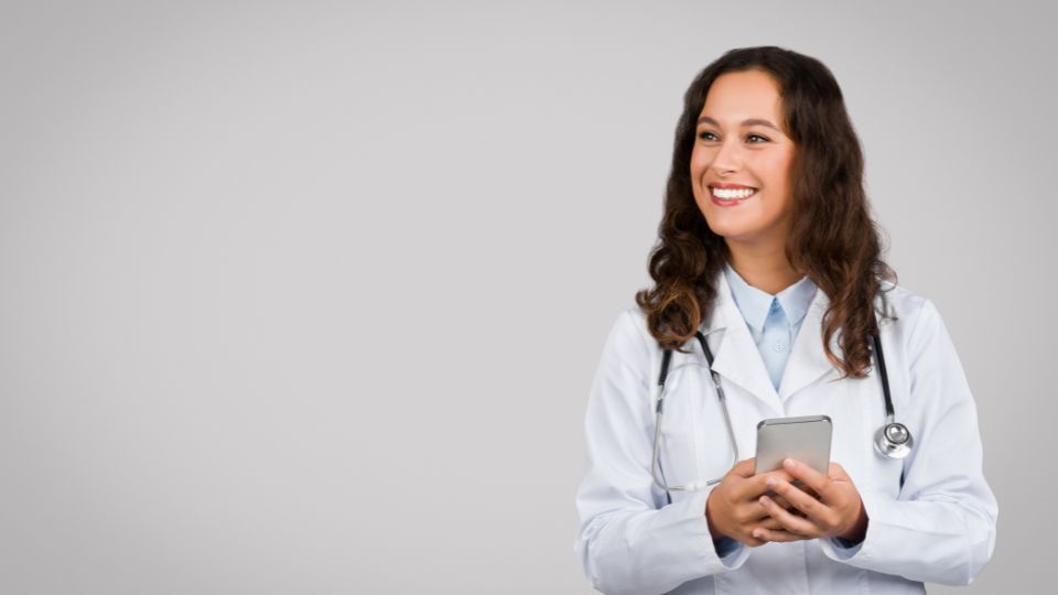 Smiling female doctor holding a smartphone, wearing a stethoscope