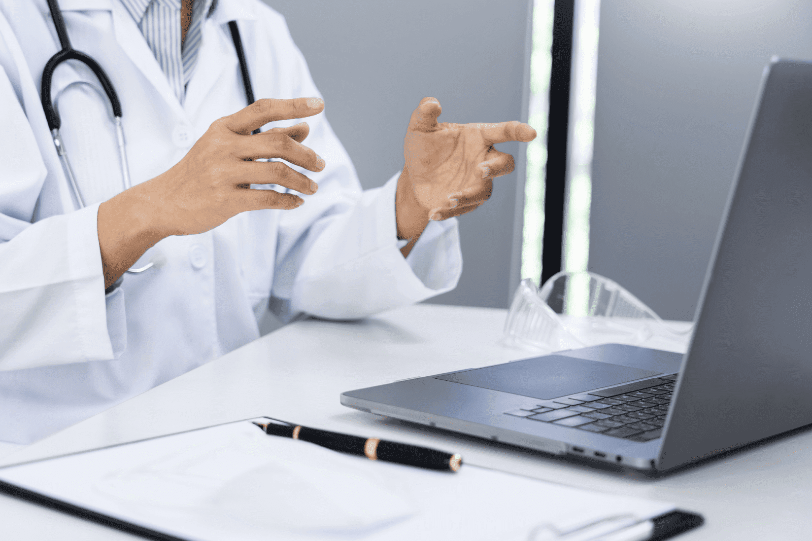 Doctor in a white coat gesturing during an online consultation.
