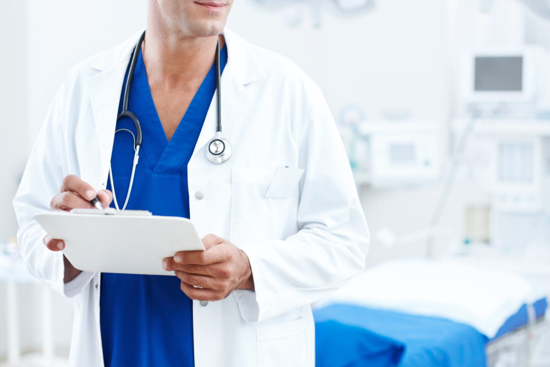 Doctor in a white coat holding a clipboard in a hospital room