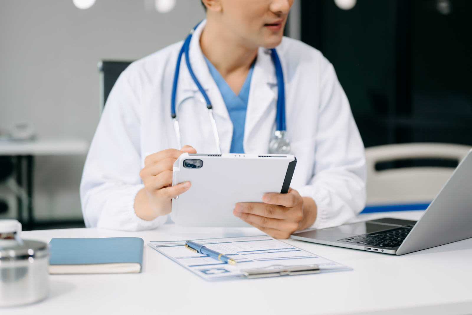 Doctor in a white coat reviewing information on a tablet at a desk
