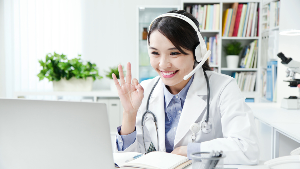 Doctor on laptop for video call giving "ok" sign with hand