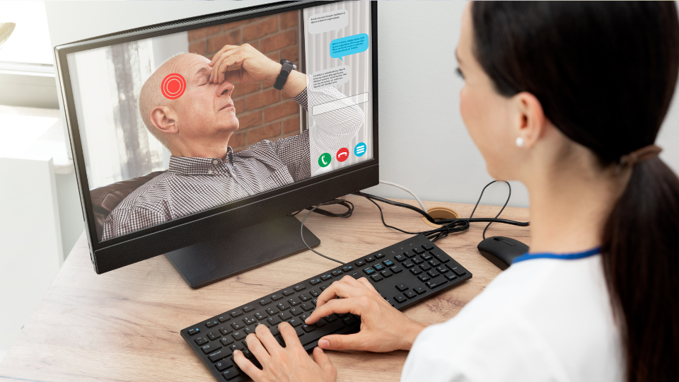 Doctor on a video call with an elderly man holding his head in pain.