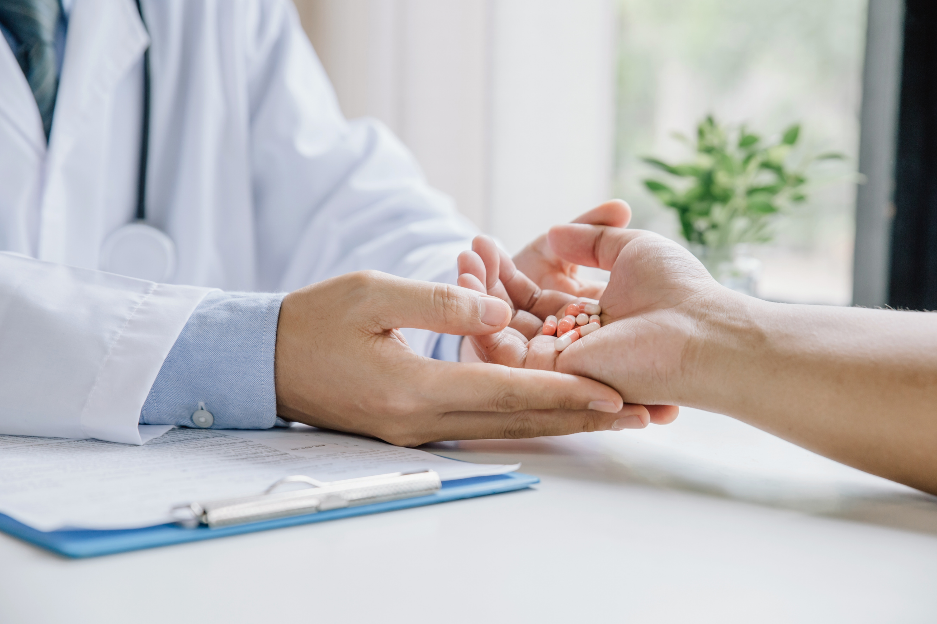 Doctor placing medication pills into a patient’s open hand
