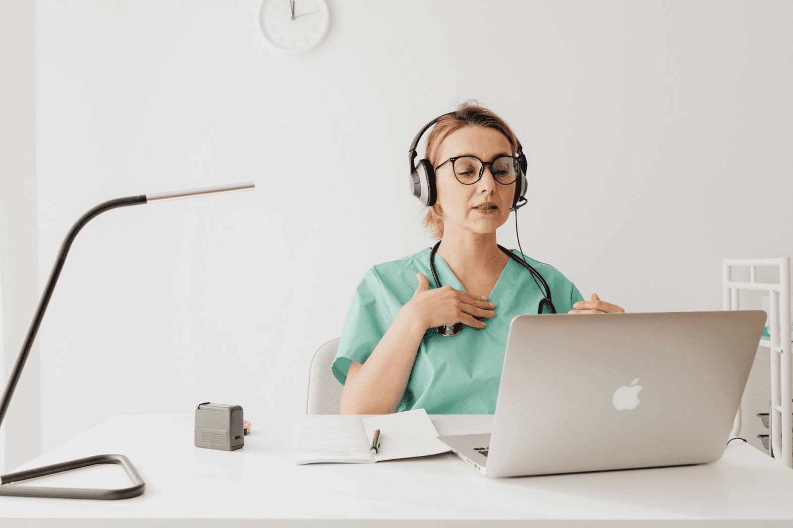 Doctor providing an online consultation via laptop, wearing a headset and green scrubs