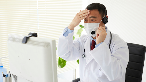 Doctor on a call rubbing forehead
