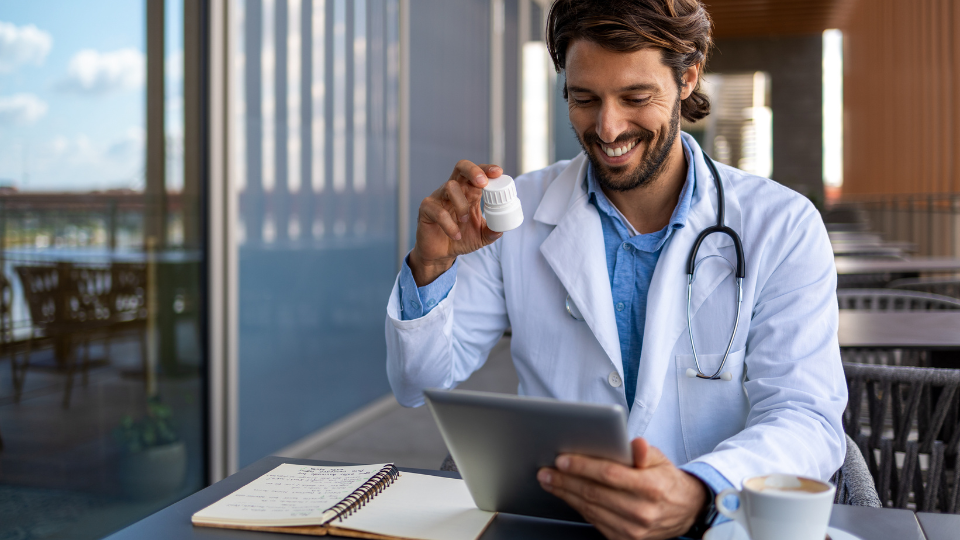 Male Doctor showing pill bottle while on telehealth video call