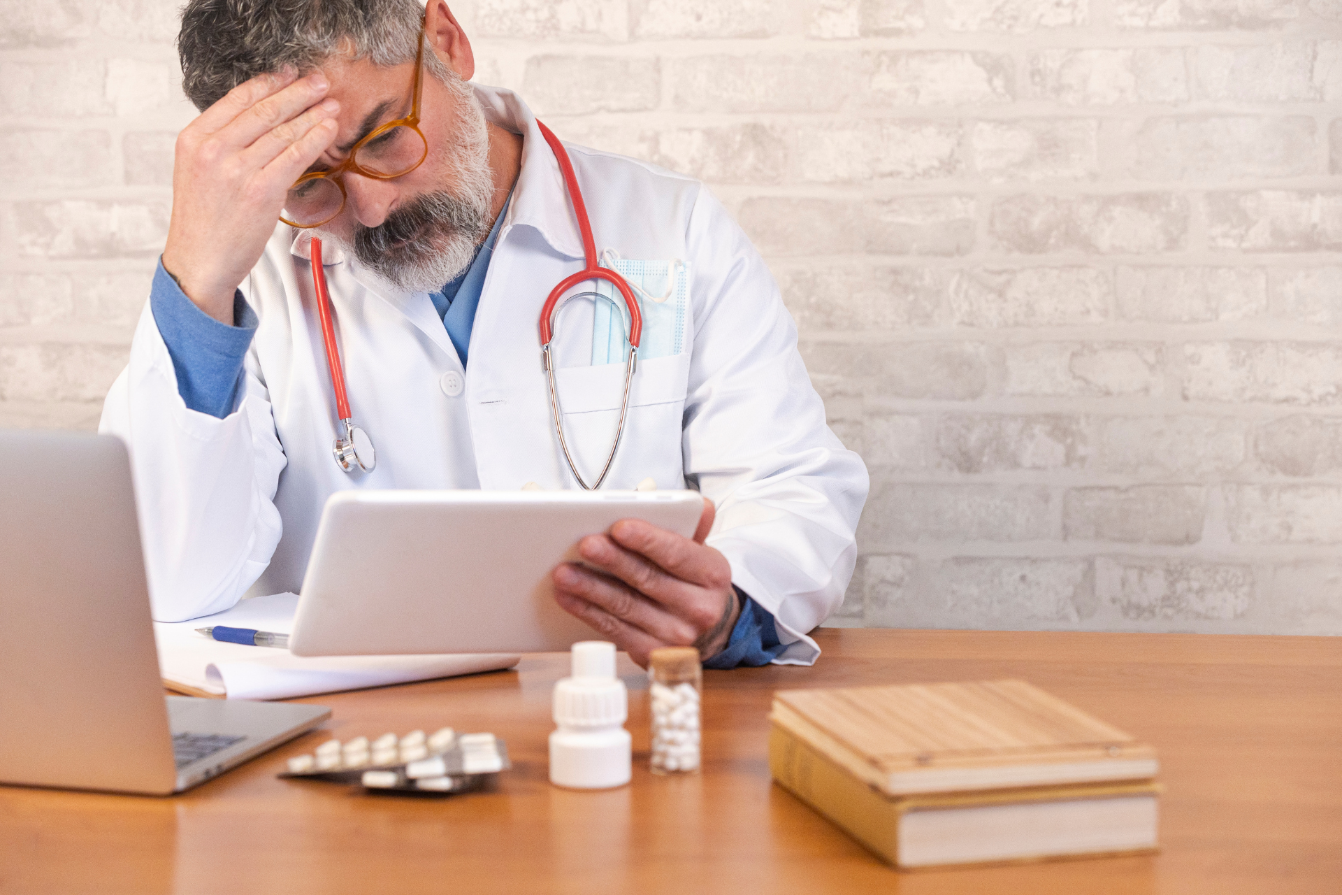 Doctor sitting at a desk reviewing information on a tablet, appearing concerned