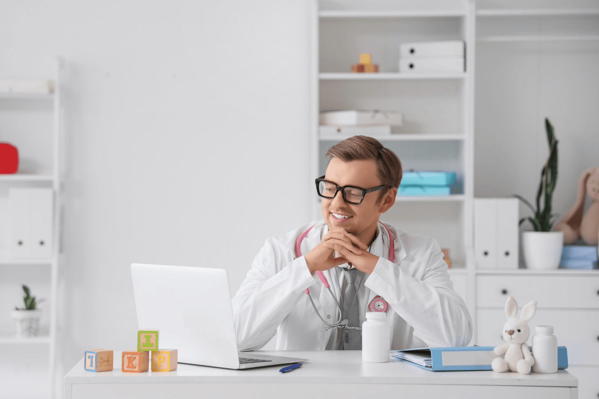 Doctor smiling at a laptop during a virtual consultation.