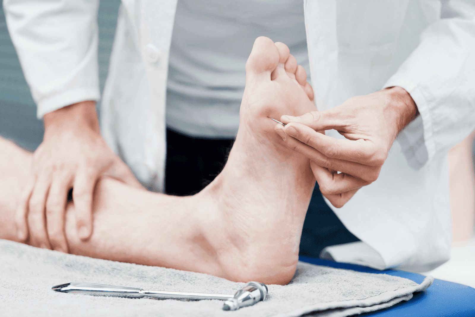 Doctor testing foot for neuropathy with pinprick exam.