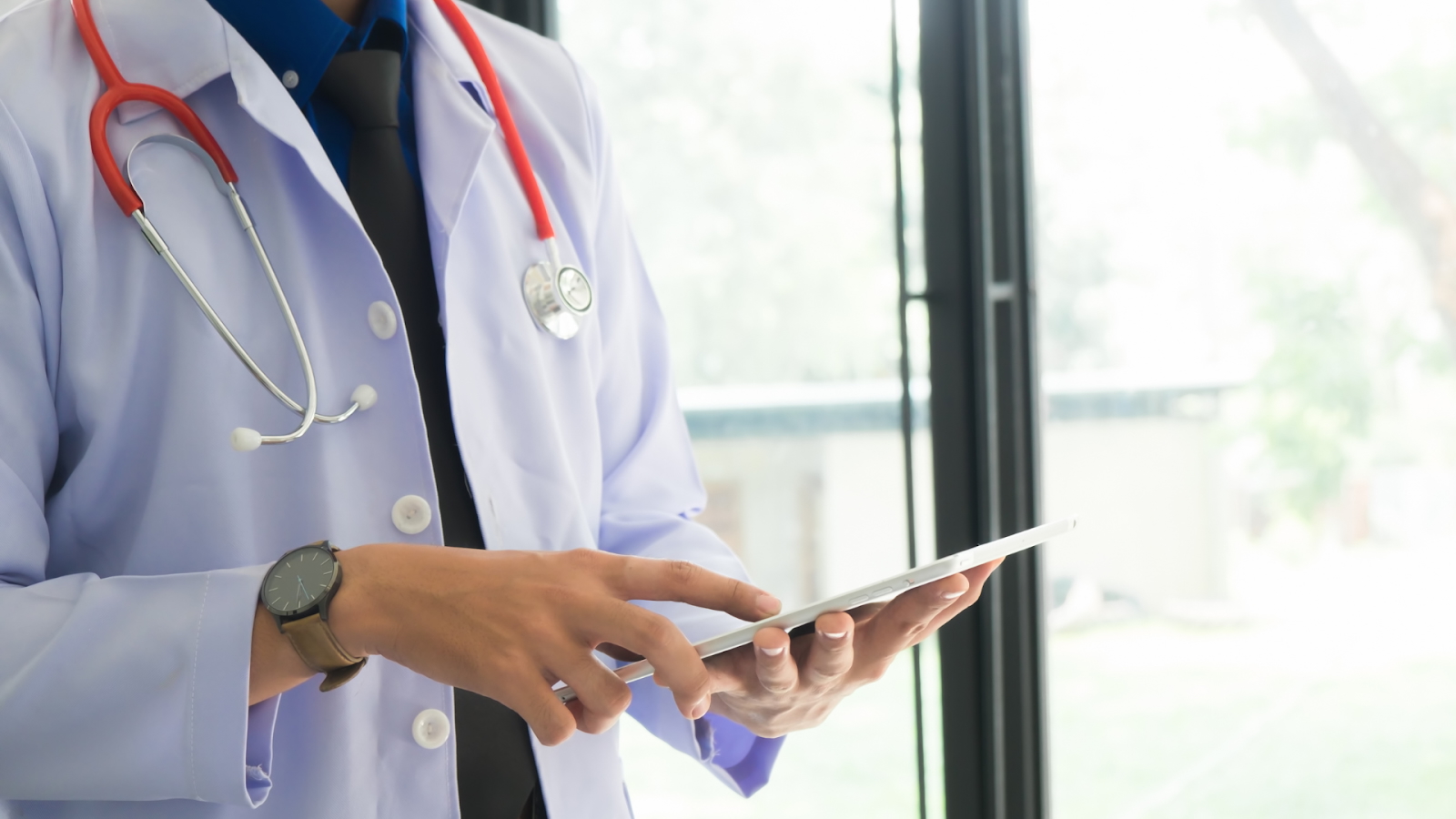 Doctor using a digital tablet with a stethoscope around the neck