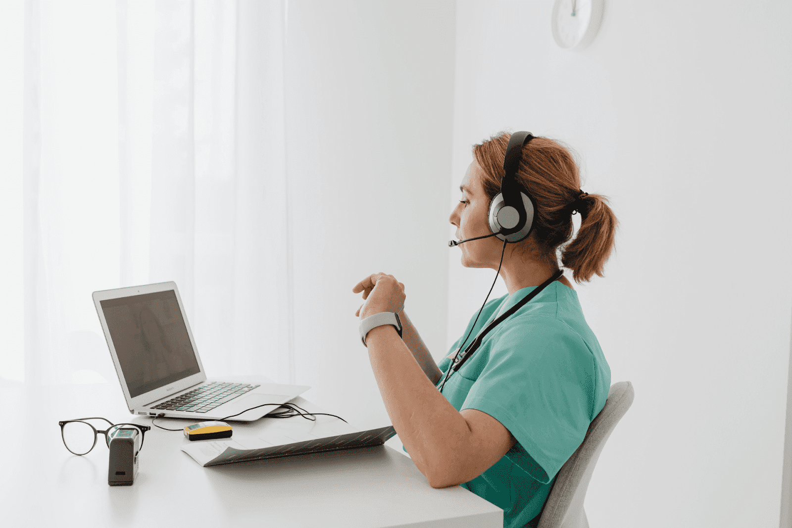 Doctor with headset providing telehealth consultation on a laptop