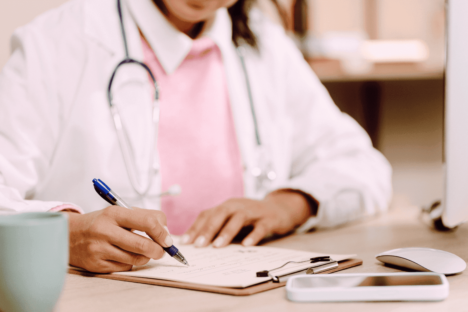 Doctor writing on a prescription form with a stethoscope around their neck