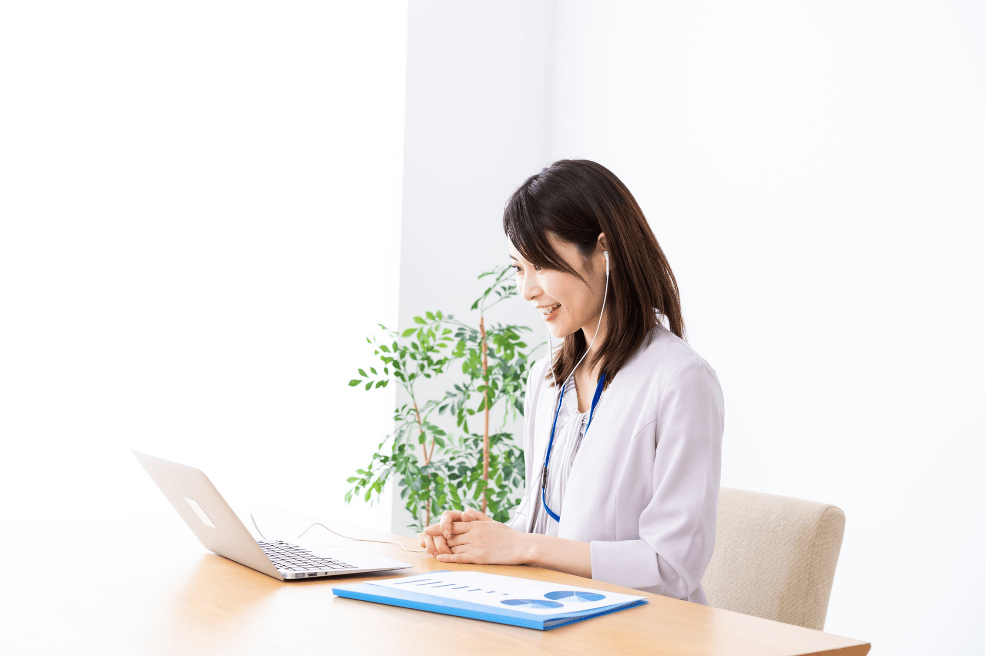 Female doctor smiling while speaking to a patient on a laptop during a virtual consultation.